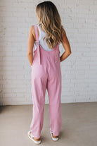 BLONDE WOMAN WEARING A CASUAL ADJUSTABLE STRAP BAGGY JUMPSUIT WITH POCKETS AND A DEEP V NECKLINE.