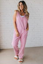 BLONDE WOMAN WEARING A CASUAL ADJUSTABLE STRAP BAGGY JUMPSUIT WITH POCKETS AND A DEEP V NECKLINE.