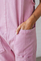 BLONDE WOMAN WEARING A CASUAL ADJUSTABLE STRAP BAGGY JUMPSUIT WITH POCKETS AND A DEEP V NECKLINE.