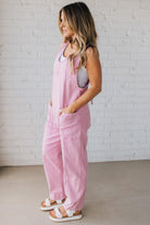 BLONDE WOMAN WEARING A CASUAL ADJUSTABLE STRAP BAGGY JUMPSUIT WITH POCKETS AND A DEEP V NECKLINE.