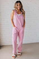 BLONDE WOMAN WEARING A CASUAL ADJUSTABLE STRAP BAGGY JUMPSUIT WITH POCKETS AND A DEEP V NECKLINE.