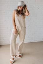 BLONDE WOMAN WEARING A CASUAL ADJUSTABLE STRAP BAGGY JUMPSUIT WITH POCKETS AND A DEEP V NECKLINE.