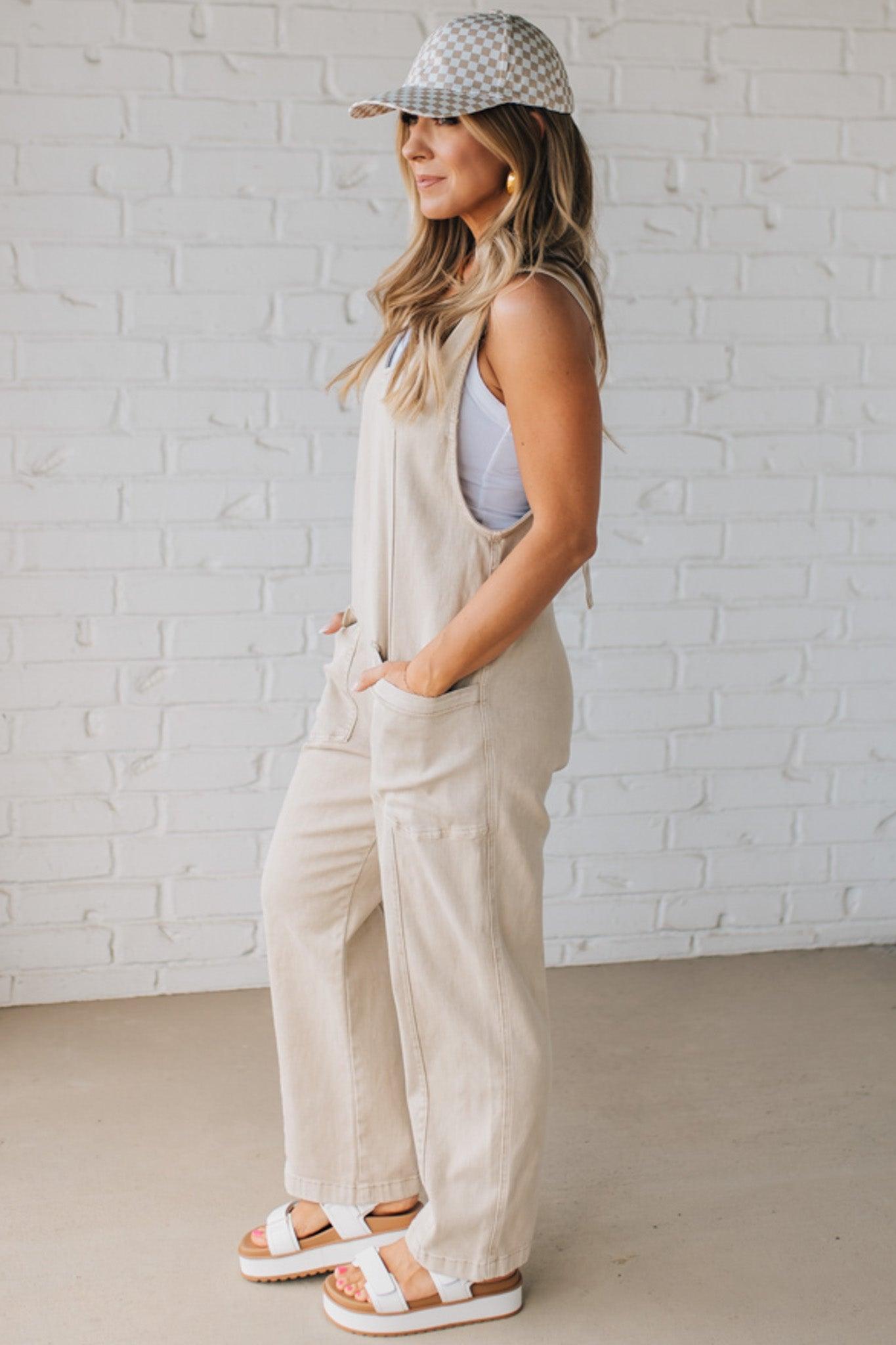 BLONDE WOMAN WEARING A CASUAL ADJUSTABLE STRAP BAGGY JUMPSUIT WITH POCKETS AND A DEEP V NECKLINE.