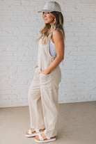 BLONDE WOMAN WEARING A CASUAL ADJUSTABLE STRAP BAGGY JUMPSUIT WITH POCKETS AND A DEEP V NECKLINE.
