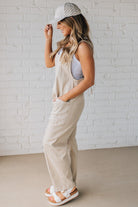 BLONDE WOMAN WEARING A CASUAL ADJUSTABLE STRAP BAGGY JUMPSUIT WITH POCKETS AND A DEEP V NECKLINE.