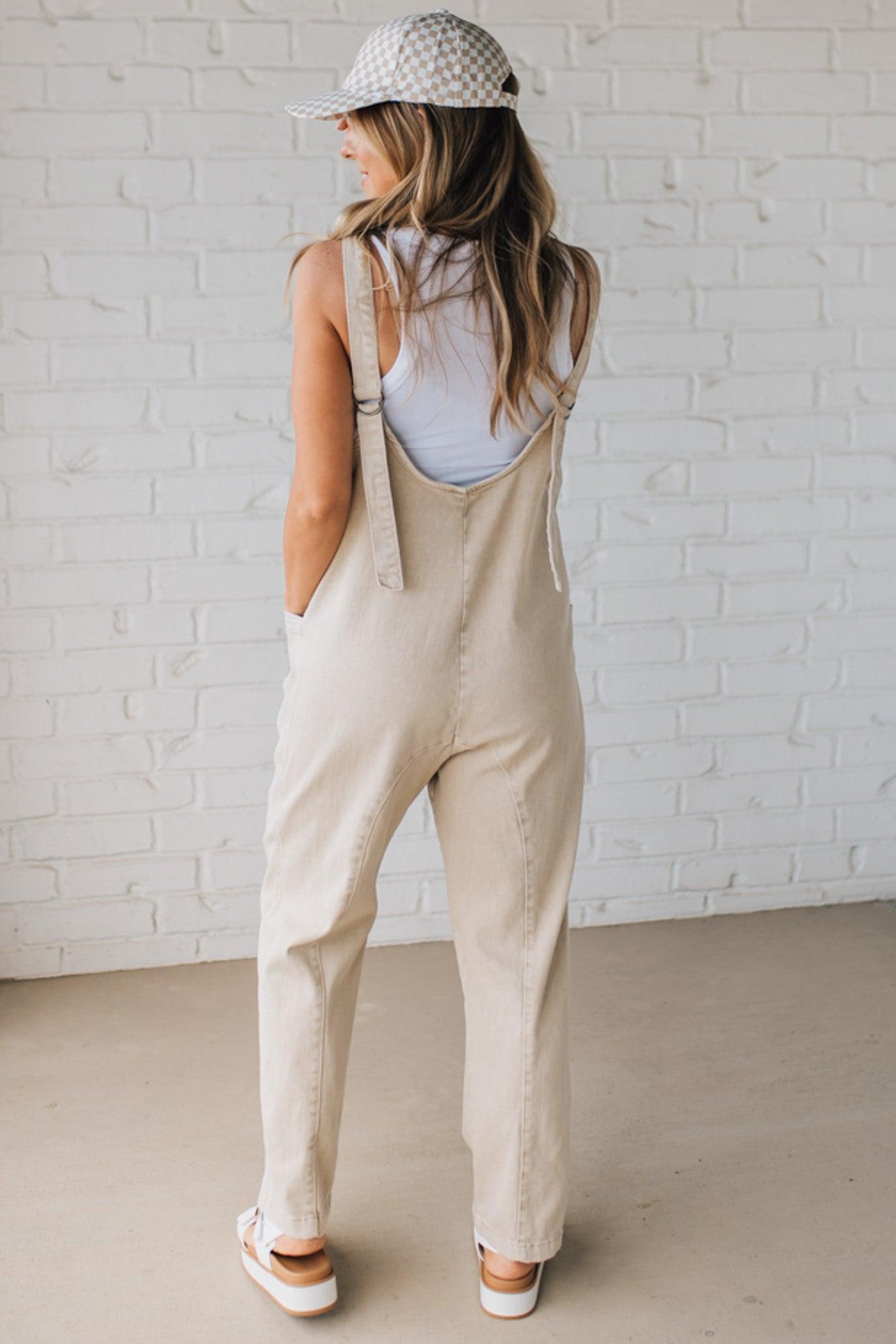 BLONDE WOMAN WEARING A CASUAL ADJUSTABLE STRAP BAGGY JUMPSUIT WITH POCKETS AND A DEEP V NECKLINE.