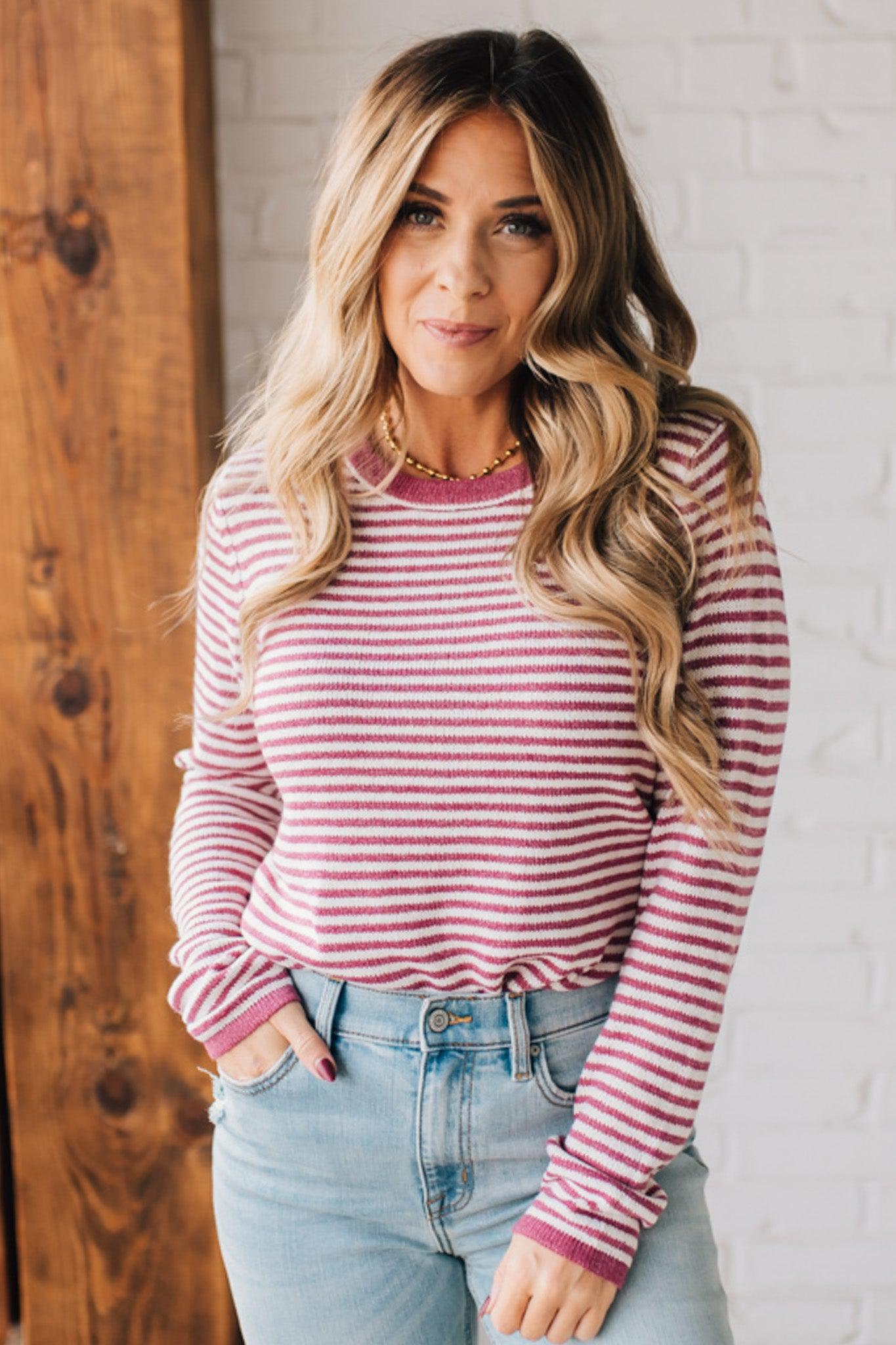 BLONDE WOMAN MODELING A LONG SLEEVE MAGENTA AND WHITE STRIPED SWEATER WITH SOLID MAGENTA ON THE NECKLINE AND SLEEVE CUFFS