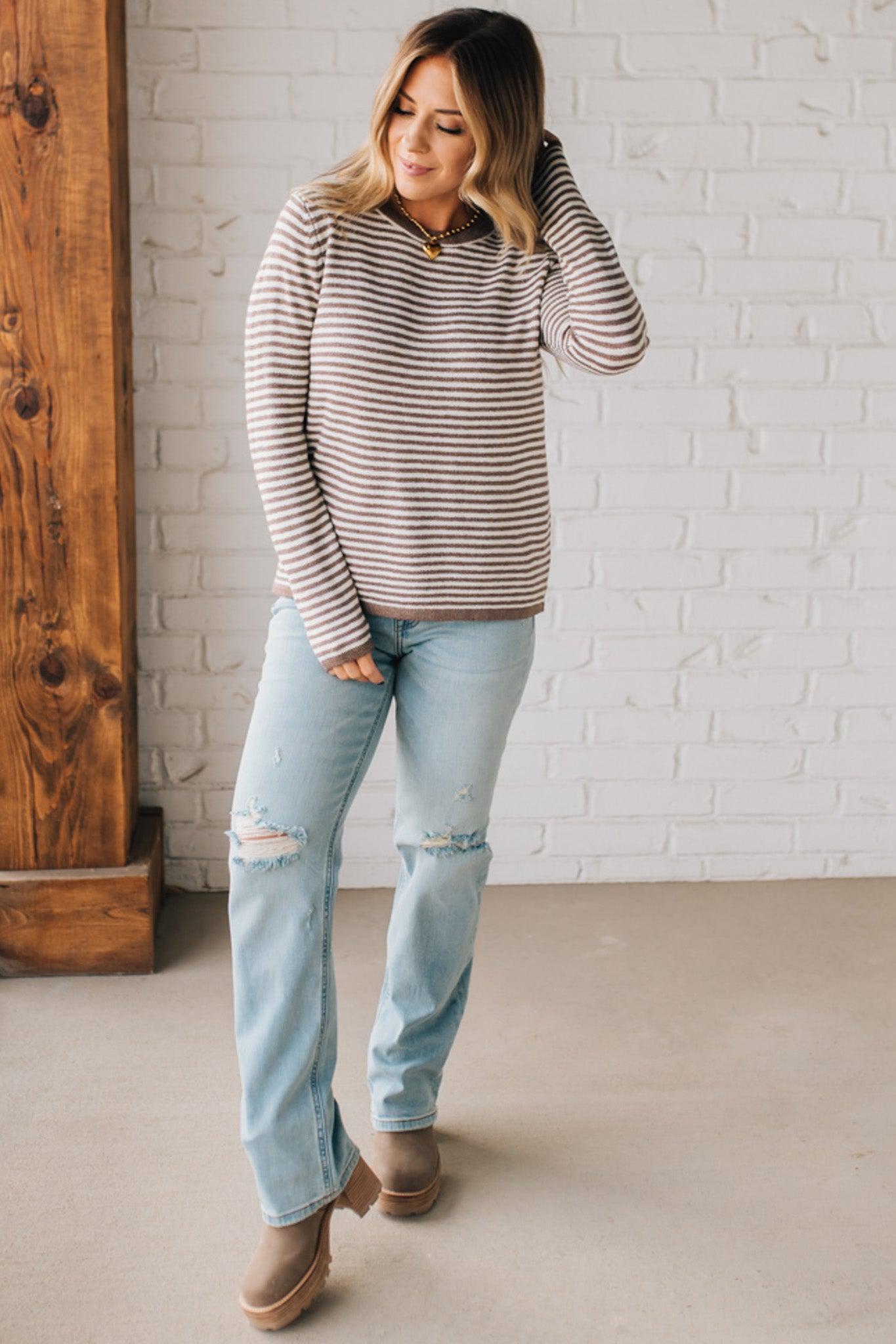 BLONDE WOMAN MODELING A LONG SLEEVE MOCHA AND WHITE STRIPED SWEATER WITH SOLID MOCHA ON THE NECKLINE AND SLEEVE CUFFS