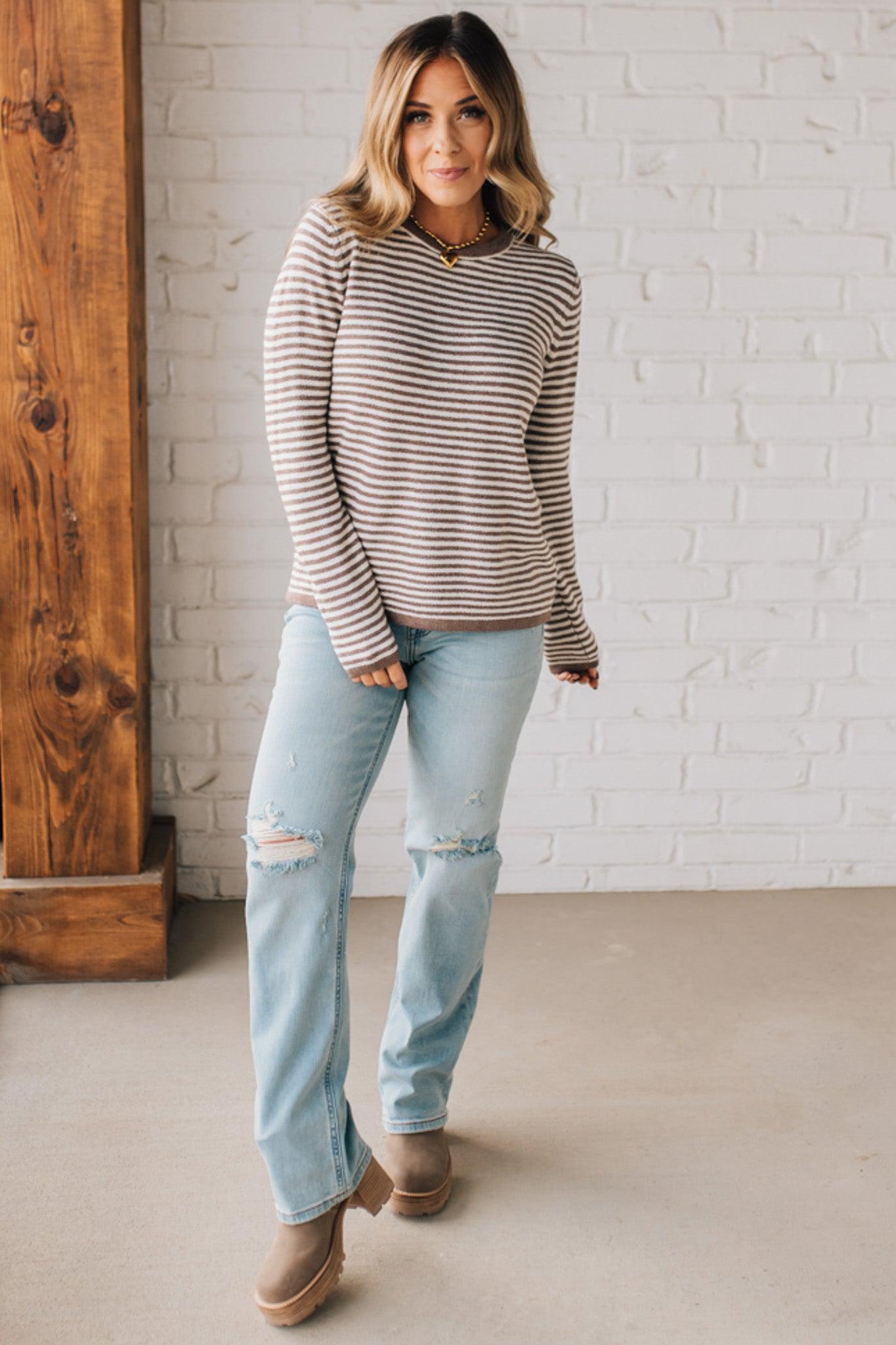 BLONDE WOMAN MODELING A LONG SLEEVE MOCHA AND WHITE STRIPED SWEATER WITH SOLID MOCHA ON THE NECKLINE AND SLEEVE CUFFS