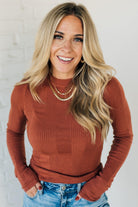 A woman wearing a navy, ribbed, slim fit sweater with a round neck, long sleeves, and tucking it into high-waisted jeans.