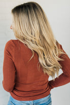 A woman wearing a solid, ribbed, slim fit sweater with a round neck, long sleeves, and tucking it into high-waisted jeans.