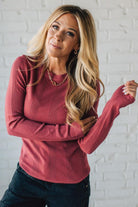 Woman wearing a red sweater in front of a white brick wall