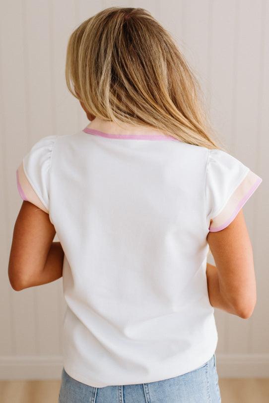 Person wearing a white top with pink trim from behind