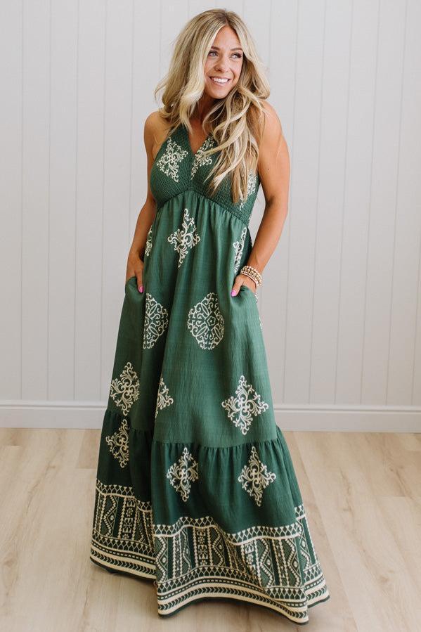 Woman wearing a green dress with white patterns in a minimal indoor setting