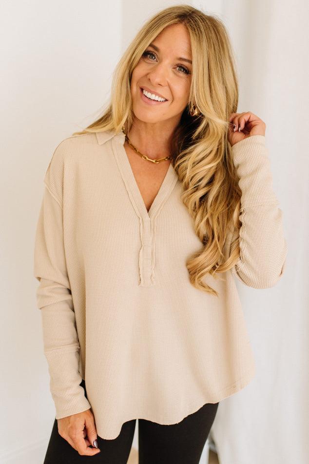 Woman wearing a beige long-sleeve top against a white background