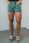 women wearing mid rise frayed shorts that have an olive green mineral wash finish