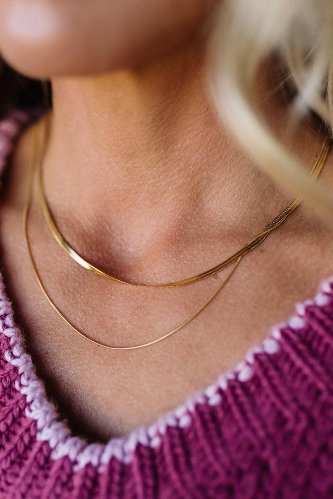 Close-up of a person wearing a gold necklace with a blurred background