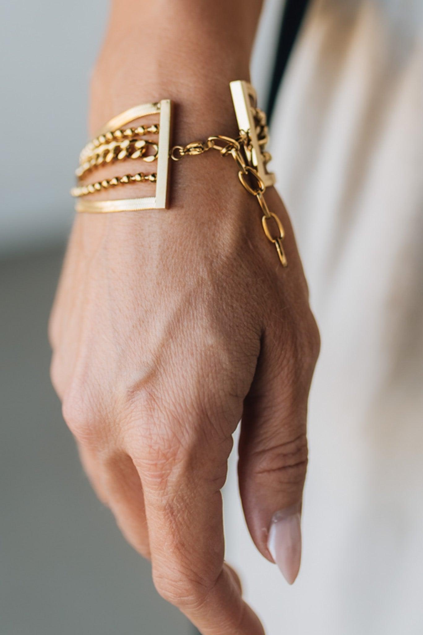 Hand wearing multiple gold bracelets on a blurred background