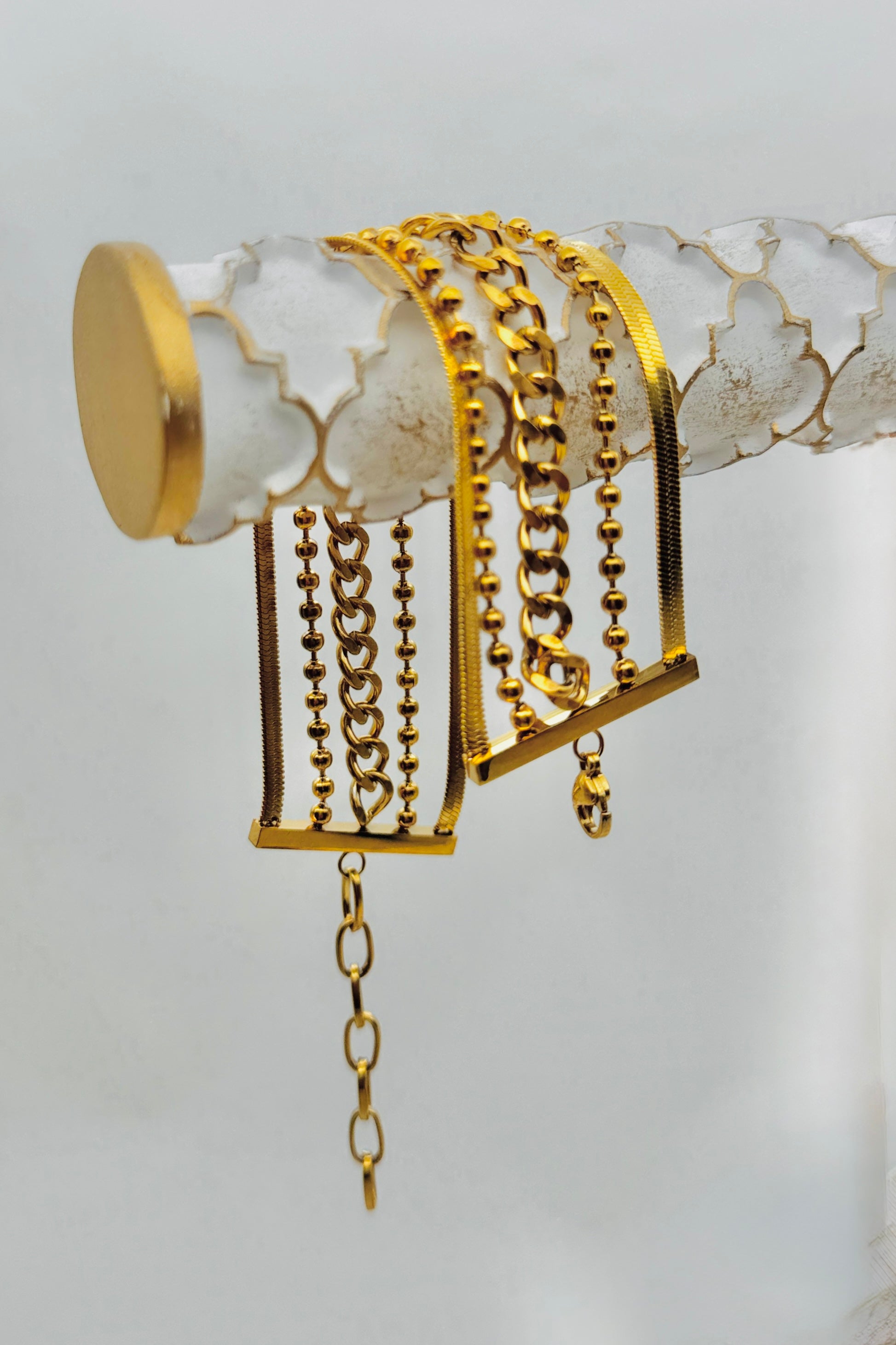 Gold chain bracelet on a white surface with a gold base