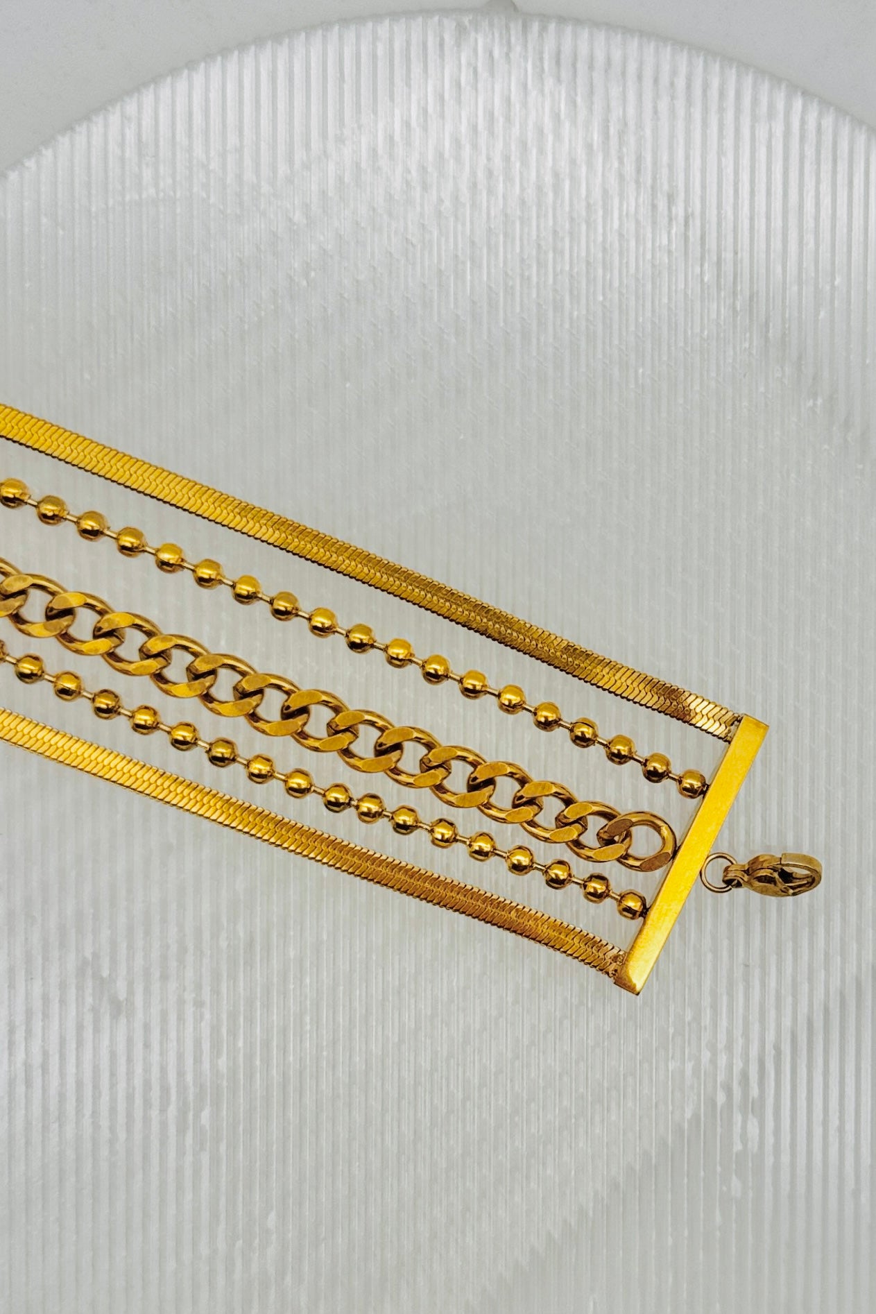 Gold chain necklace on a textured white background