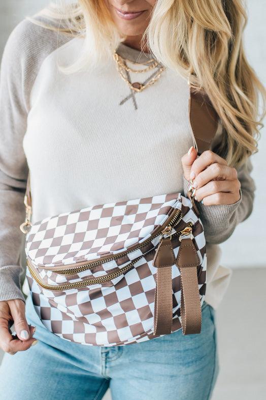 Woman holding a checkered bag with a neutral background