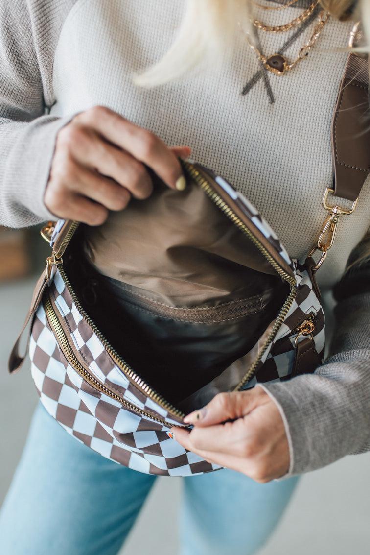 Person opening a checkered handbag with a neutral background