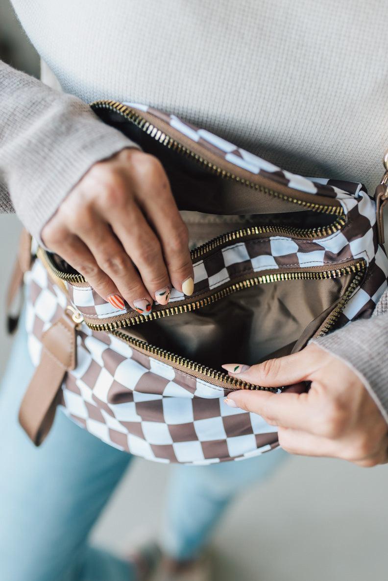 Person opening a checkered handbag with a neutral background