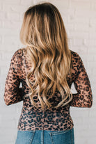 BLONDE WOMAN WEARING ANIMAL PRINTED LETTUCE EDGE MESH MOCK NECK TOP