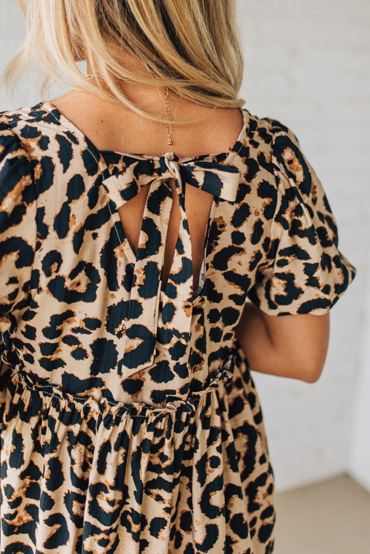 BLONDE WOMAN WEARING A LEOPARD PRINT WOVEN PUFF SLEEVES DRESS WITH PATCH POCKETS.