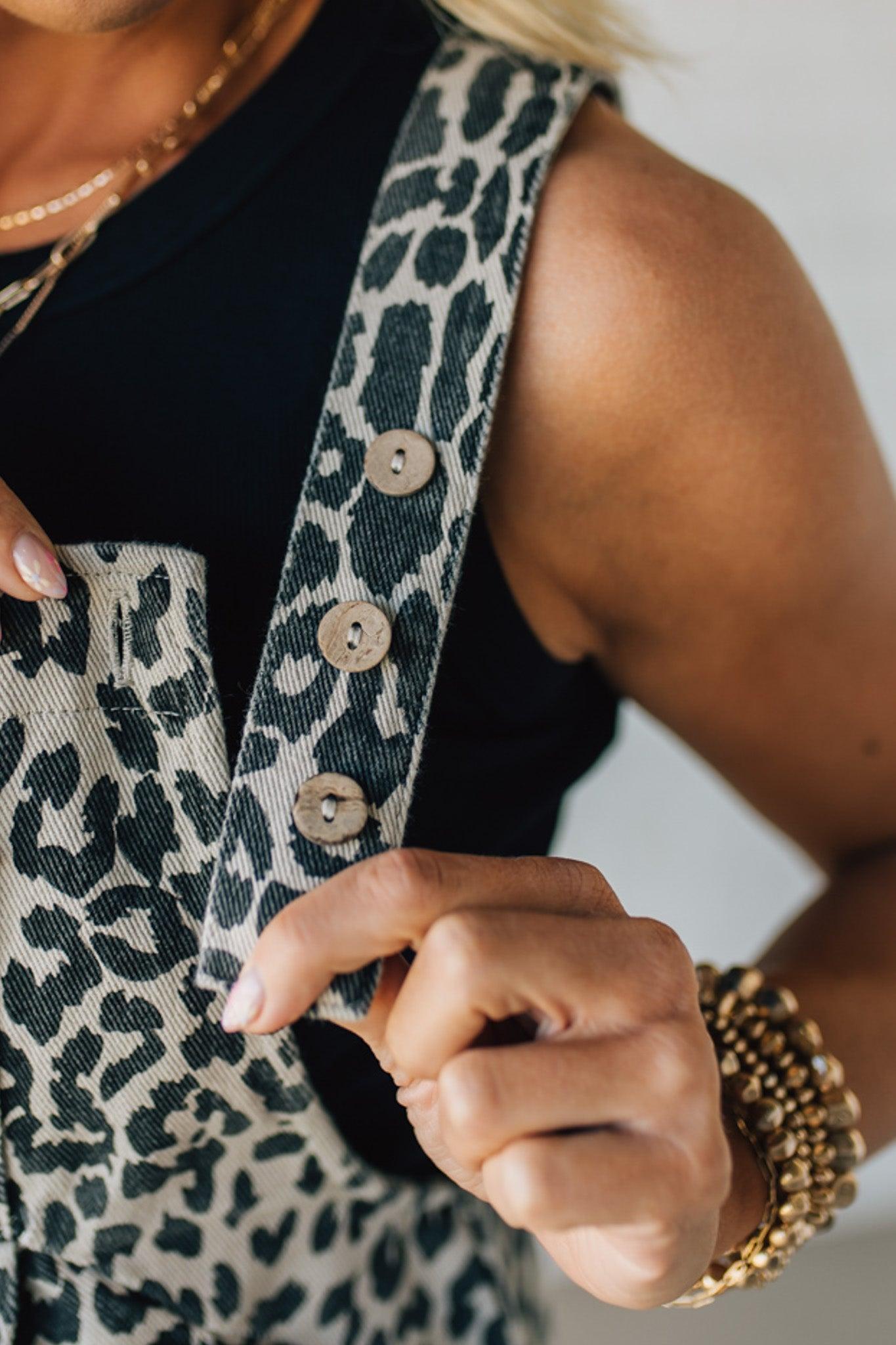 BLONDE WOMAN WEARING CREAM AND BLACK LEOPARD PRINT PINTUCKED DETAIL SHORT OVERALL WITH POCKETS.