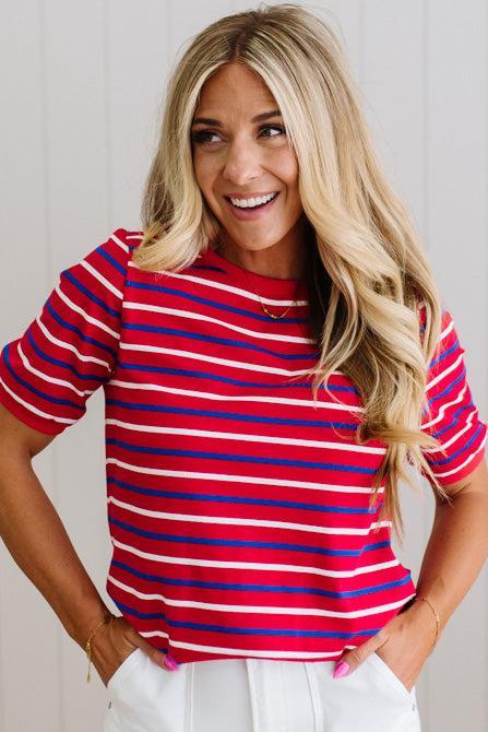 Woman wearing a red and blue striped shirt with a plain background