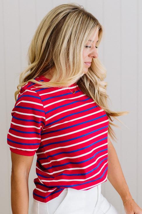 Woman wearing a red and blue striped shirt against a plain background
