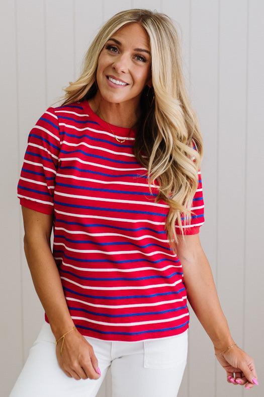 Woman wearing a red and blue striped shirt against a plain background