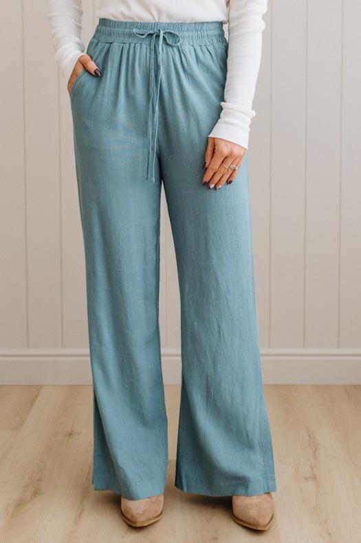 Person wearing light blue pants with a white top against a neutral background