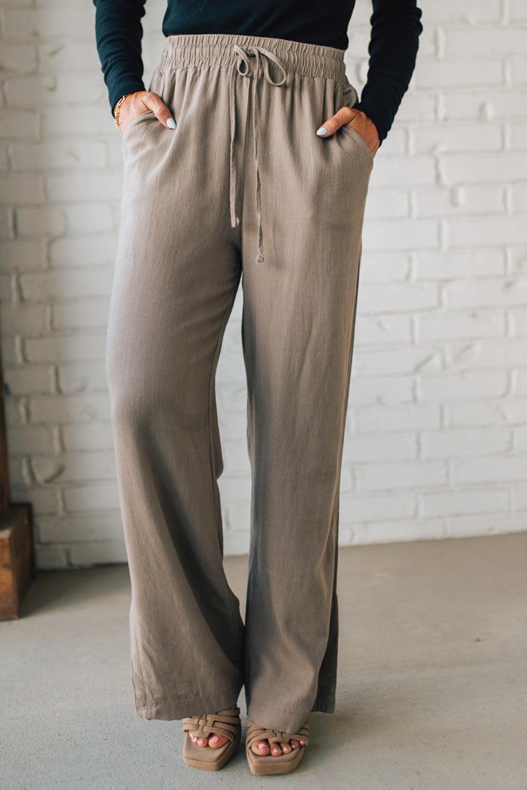 Person wearing beige wide-leg pants with a white brick wall background