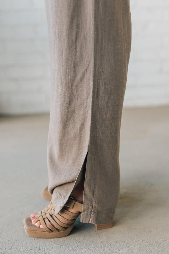 Close-up of beige pants and sandals on a neutral background