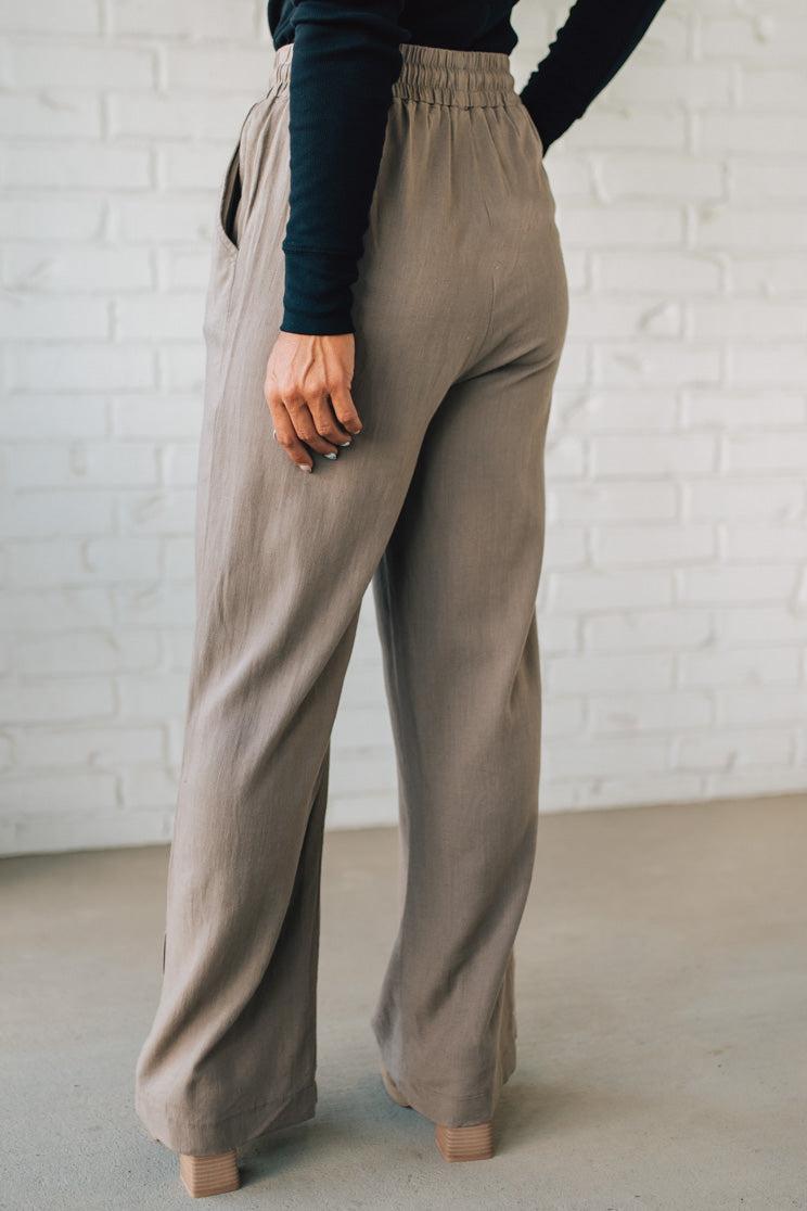 Person wearing beige pants with a white brick wall background