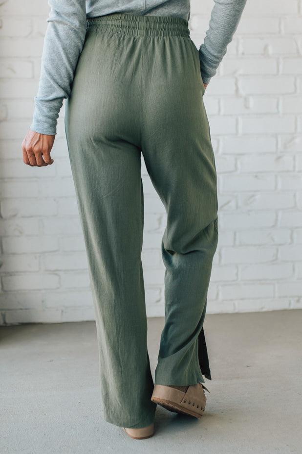 Person wearing green pants with a white brick wall background