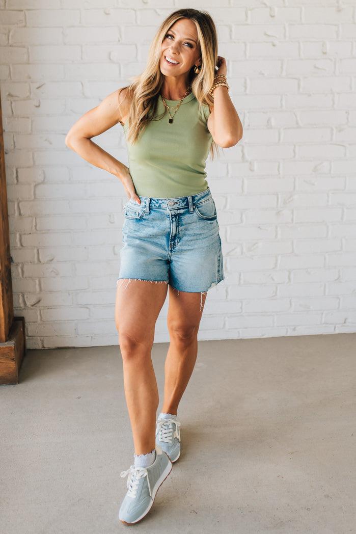 Woman wearing Acid Washed Raw Hem Shorts in Mid Rise.