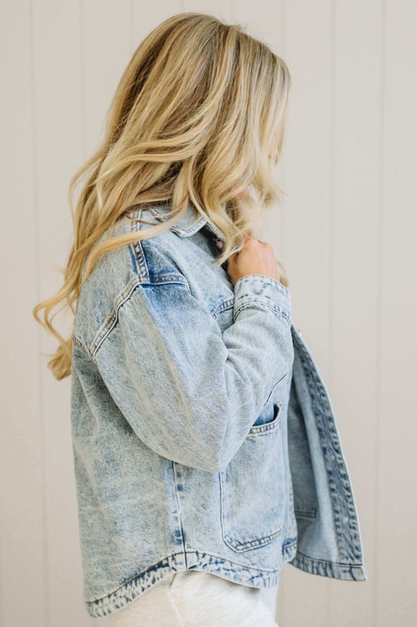 Person wearing a light blue denim jacket against a plain background