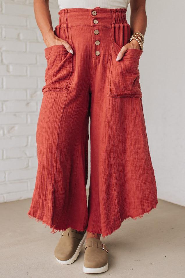 Person wearing red wide-leg pants with a white brick wall background