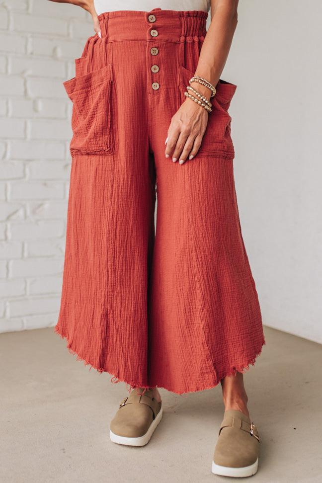 Person wearing red wide-leg pants with a white brick wall background