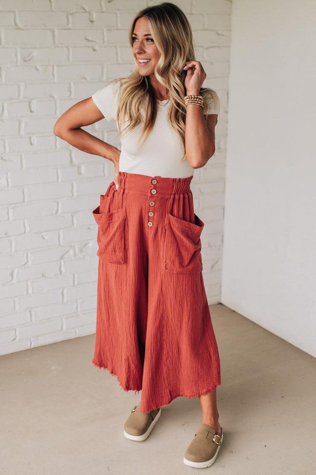 Woman wearing a white top and red skirt with a white brick wall background