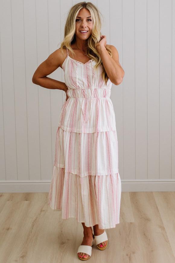 Woman wearing a striped dress standing against a white paneled wall.