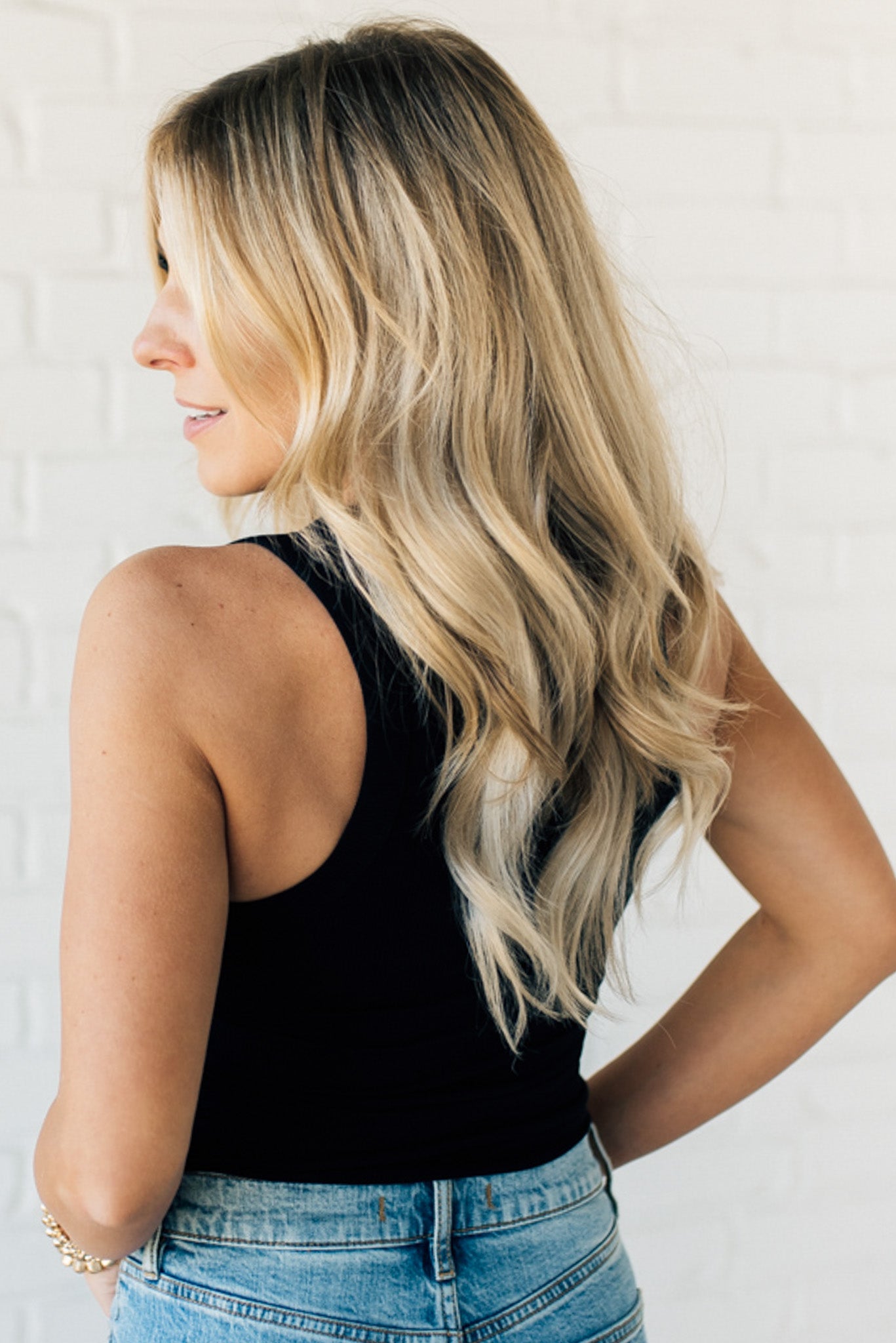 Blonde woman wearing a mini ribbed scoop neck tank with wide strap and solid neutral color.