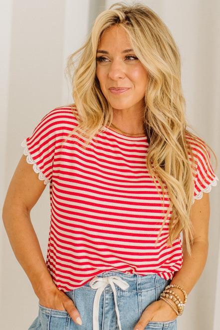 Woman wearing a red and white striped shirt with blue jeans against a plain background