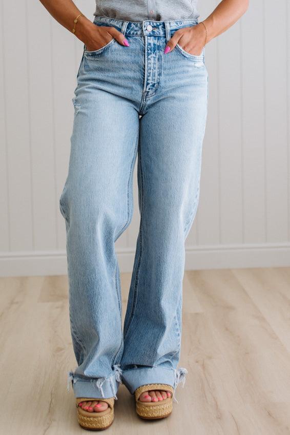 Person wearing light blue flared jeans with a neutral background