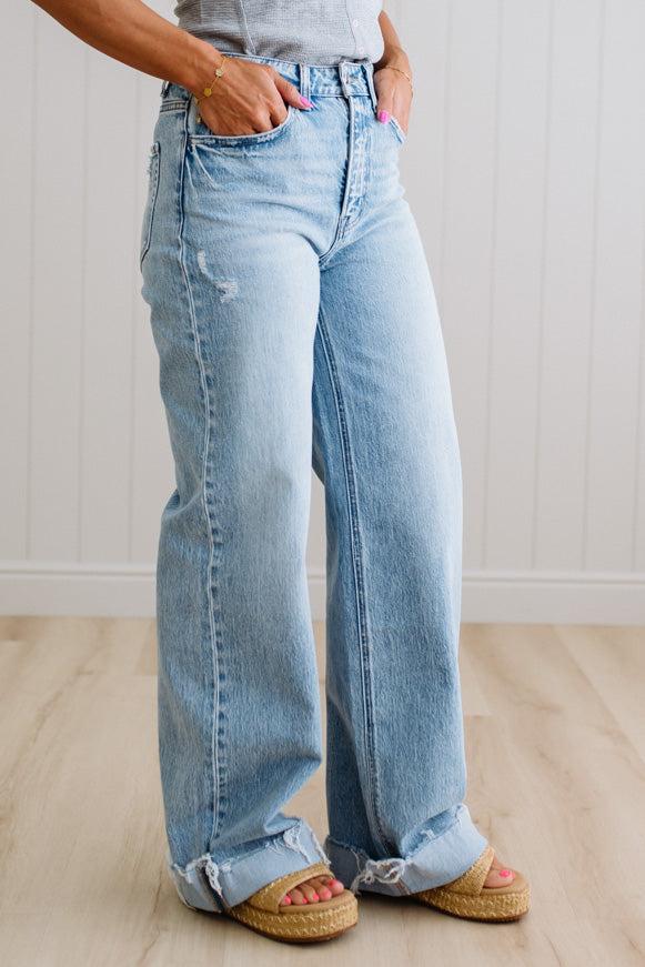 Person wearing light blue wide-leg jeans with a neutral background