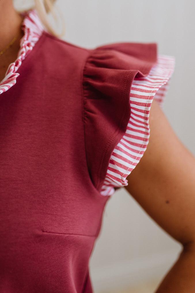 Red dress with white and red striped trim on a neutral background