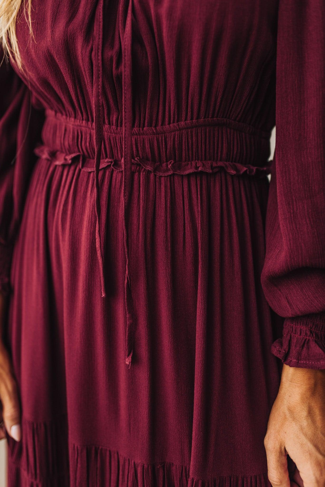 Close-up of a burgundy dress with long sleeves and a fitted waist.